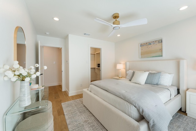 bedroom featuring light wood-type flooring, a walk in closet, a ceiling fan, and recessed lighting