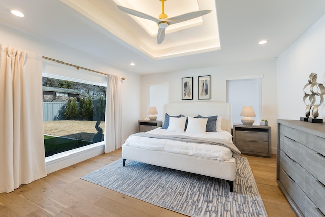 bedroom with light wood-type flooring, a tray ceiling, a ceiling fan, and recessed lighting