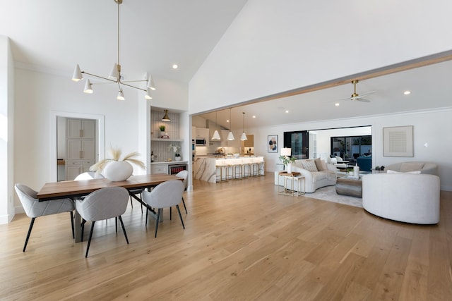 dining room with light wood-style floors, crown molding, and a towering ceiling