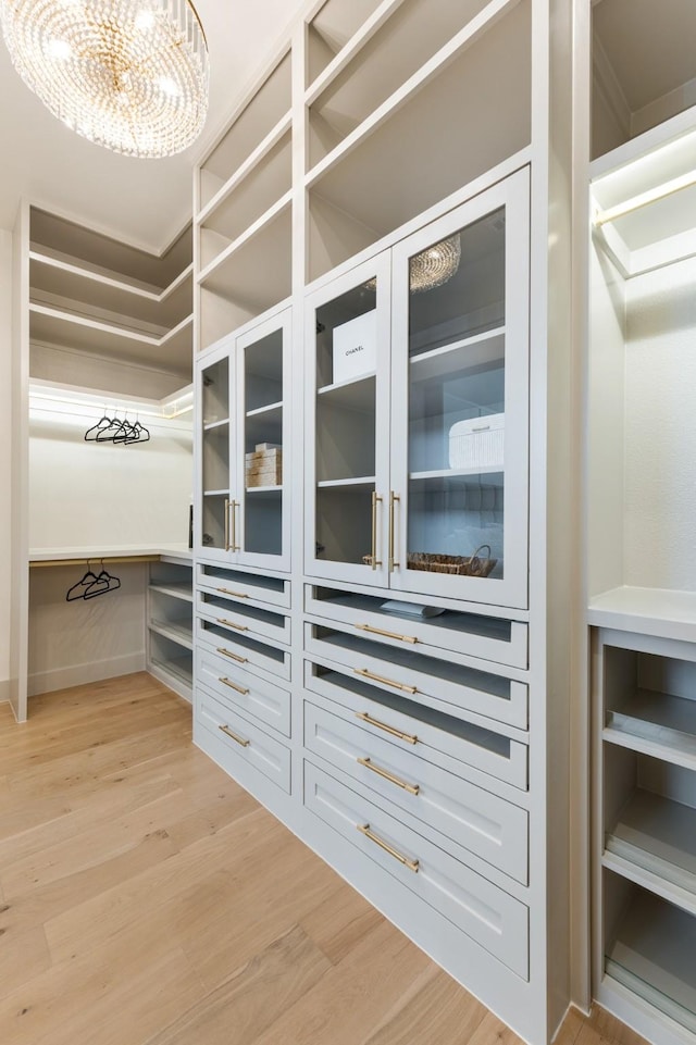 walk in closet featuring an inviting chandelier and light wood-style floors