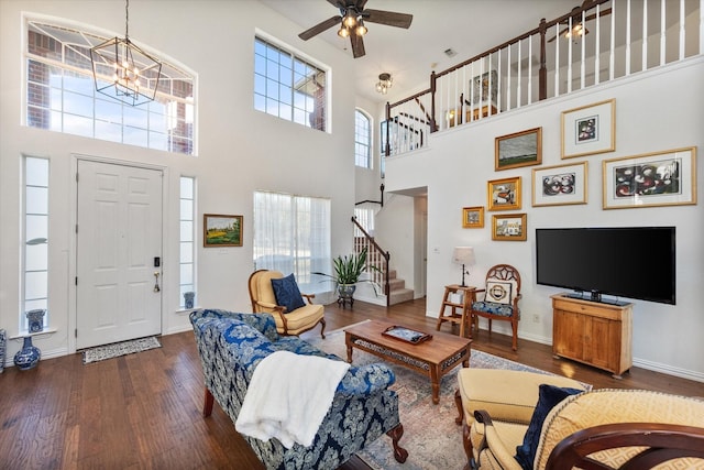 living area with stairs, ceiling fan with notable chandelier, wood finished floors, and baseboards