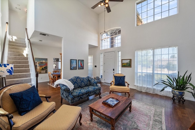 living area with visible vents, baseboards, stairs, wood finished floors, and a ceiling fan