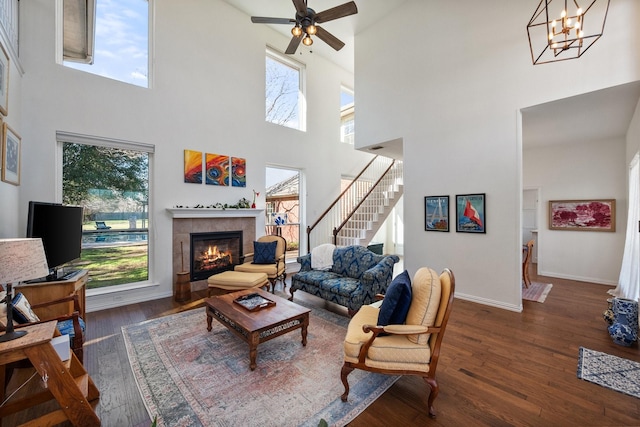 living area with a wealth of natural light, stairway, a fireplace, and wood finished floors