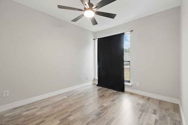 empty room featuring light wood-type flooring, a ceiling fan, and baseboards