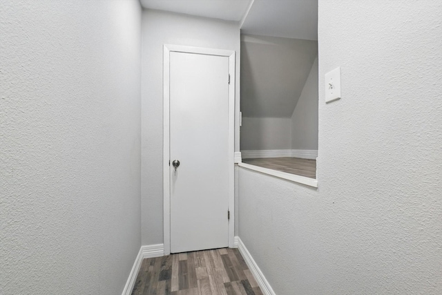 doorway to outside with a textured wall, baseboards, and wood finished floors