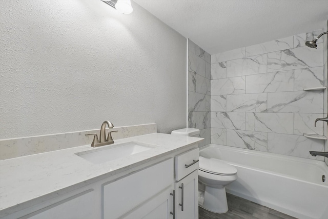 bathroom with a textured wall, toilet, wood finished floors, bathtub / shower combination, and vanity