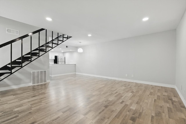 unfurnished living room with light wood finished floors, stairway, visible vents, and recessed lighting