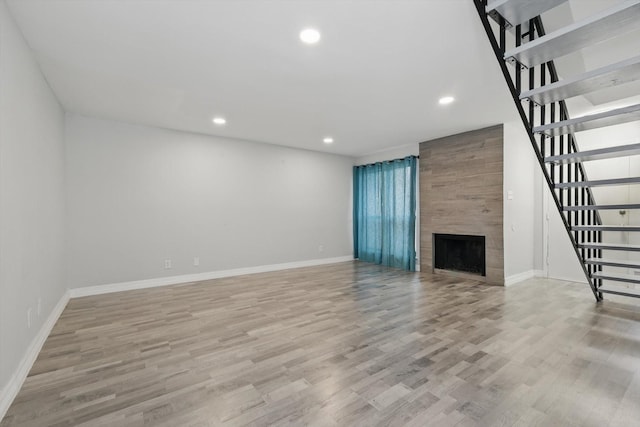 unfurnished living room with a fireplace, recessed lighting, stairway, light wood-type flooring, and baseboards