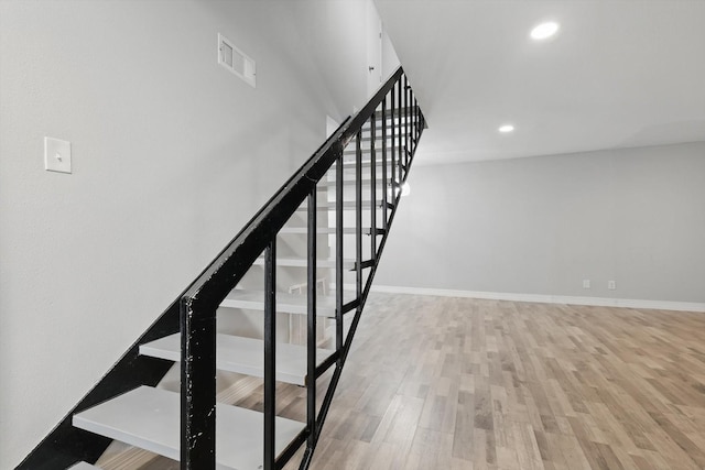 stairway with recessed lighting, visible vents, baseboards, and wood finished floors