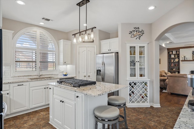 kitchen featuring a sink, visible vents, appliances with stainless steel finishes, a center island, and tasteful backsplash