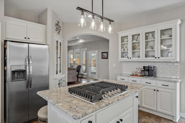 kitchen with appliances with stainless steel finishes, arched walkways, white cabinetry, and tasteful backsplash