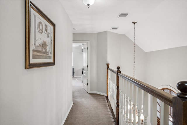 corridor with carpet, visible vents, vaulted ceiling, and an upstairs landing