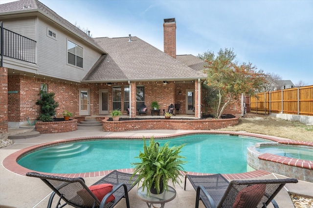 view of pool featuring a patio area, fence, and a pool with connected hot tub