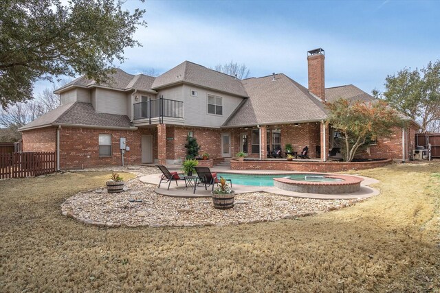 back of property featuring brick siding, a patio, a balcony, and fence