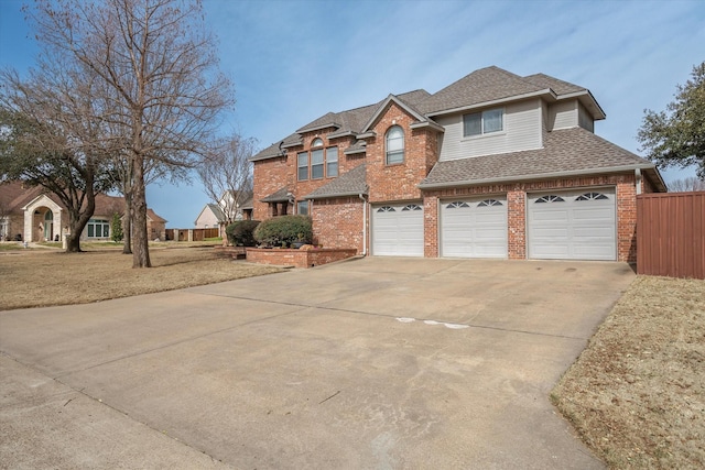 traditional-style house with a garage, brick siding, a shingled roof, fence, and concrete driveway