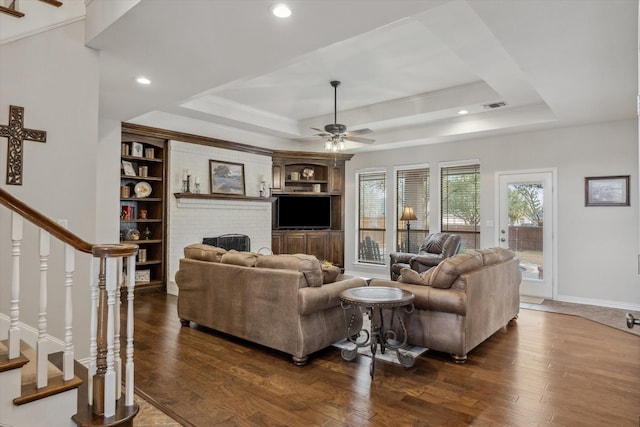 living room featuring a raised ceiling, visible vents, dark wood finished floors, and stairway