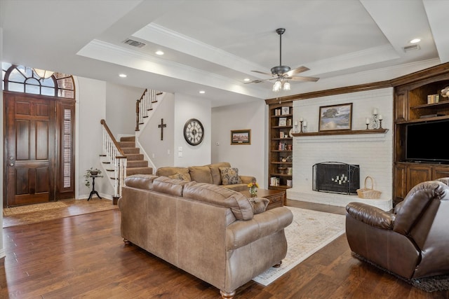 living room with stairway, visible vents, a raised ceiling, and dark wood-type flooring