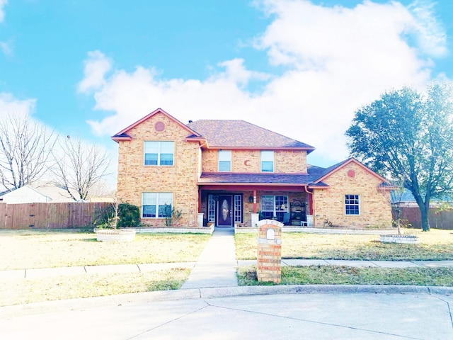 traditional-style home with a shingled roof, brick siding, and fence