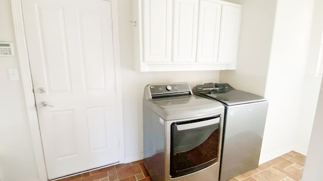 laundry room featuring brick floor, cabinet space, independent washer and dryer, and baseboards