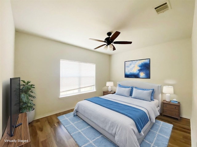 bedroom featuring a ceiling fan, visible vents, baseboards, and wood finished floors