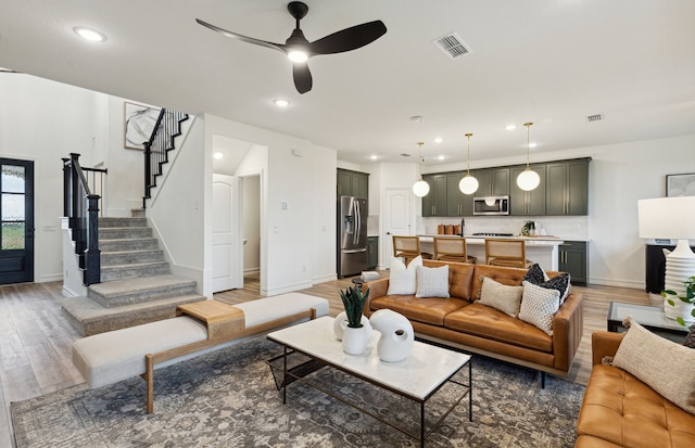 living room with light wood finished floors, recessed lighting, visible vents, baseboards, and stairs