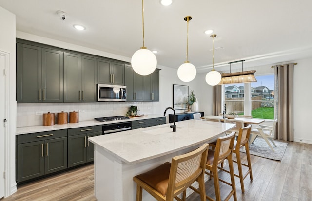 kitchen featuring tasteful backsplash, stainless steel microwave, a sink, gas cooktop, and light stone countertops