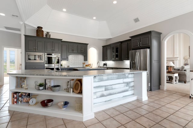 kitchen with visible vents, appliances with stainless steel finishes, arched walkways, open shelves, and a large island
