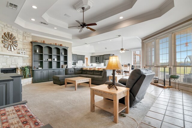 living area featuring a tray ceiling, visible vents, and ceiling fan
