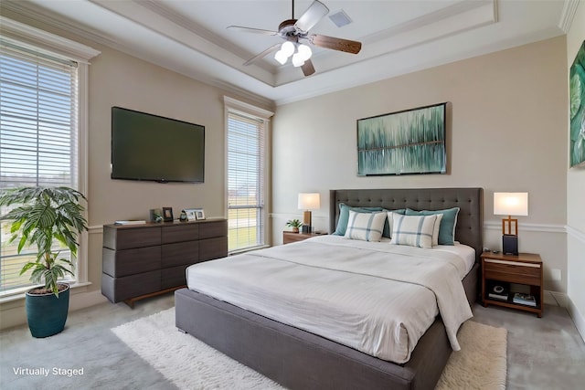 bedroom featuring ornamental molding, light carpet, a ceiling fan, and a raised ceiling
