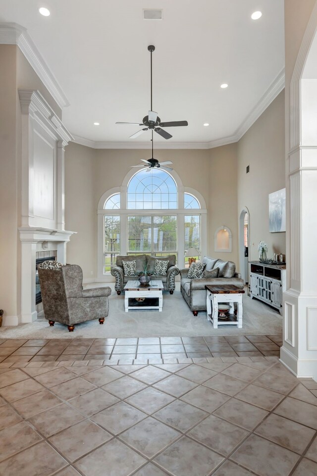 living area with recessed lighting, ornamental molding, a large fireplace, a high ceiling, and a ceiling fan