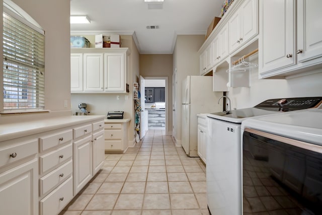 kitchen featuring visible vents, ornamental molding, washer and clothes dryer, light tile patterned floors, and freestanding refrigerator