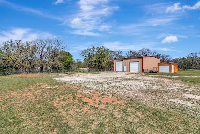view of yard featuring fence, an outdoor structure, and a garage