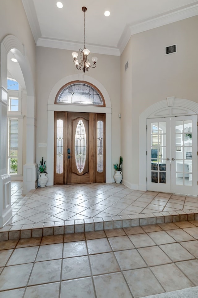 entryway with ornamental molding, visible vents, an inviting chandelier, and tile patterned floors