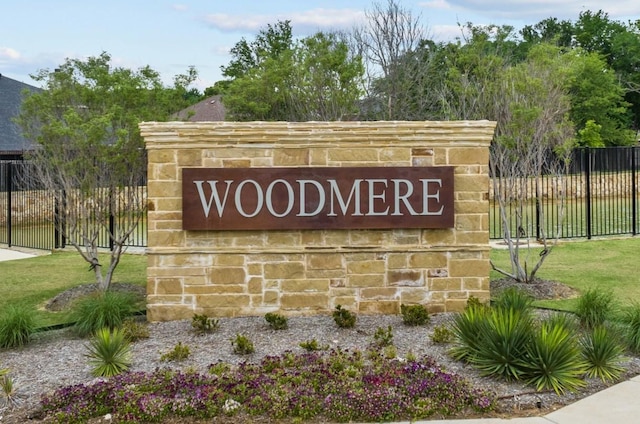 community / neighborhood sign with a garage, a lawn, and fence