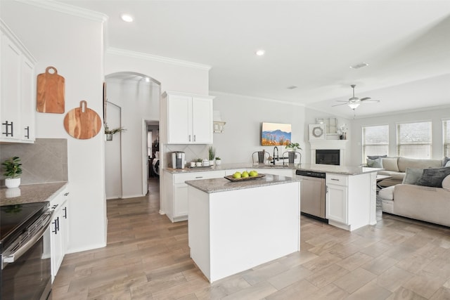 kitchen with arched walkways, a ceiling fan, open floor plan, a peninsula, and stainless steel appliances