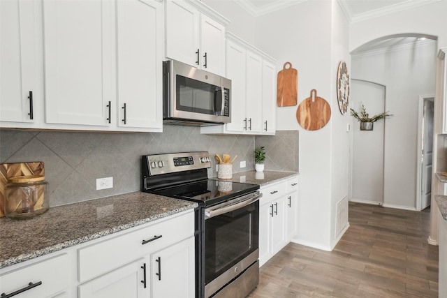 kitchen featuring stone countertops, ornamental molding, stainless steel appliances, light wood-type flooring, and white cabinetry