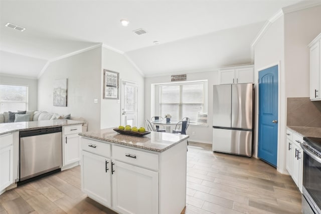 kitchen with lofted ceiling, appliances with stainless steel finishes, a wealth of natural light, and visible vents