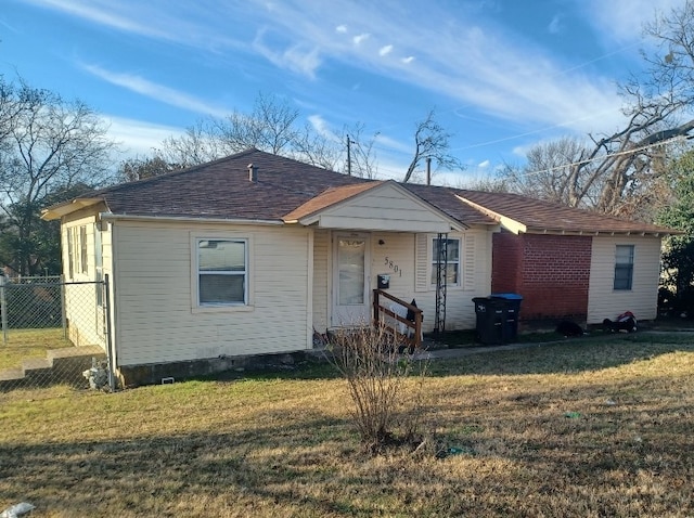 view of front of house with roof with shingles, fence, and a front lawn