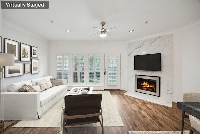 living area with a ceiling fan, ornamental molding, wood finished floors, and a high end fireplace