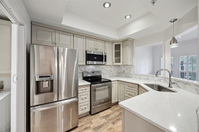 kitchen with tasteful backsplash, a raised ceiling, cream cabinets, appliances with stainless steel finishes, and a sink