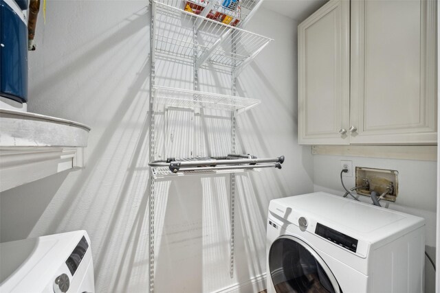 laundry area with cabinet space and washer / dryer