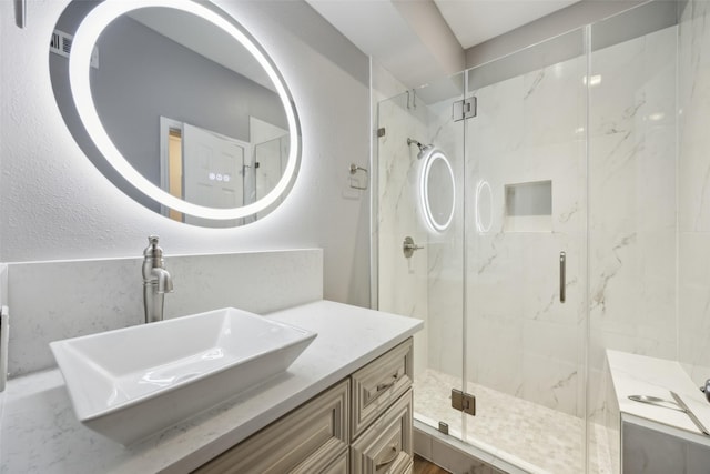 full bathroom with a marble finish shower and vanity