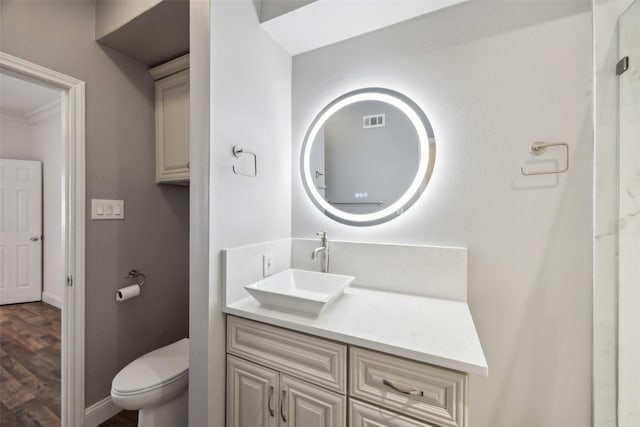 bathroom featuring baseboards, visible vents, toilet, wood finished floors, and vanity