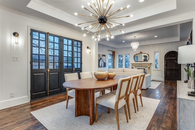 dining room with a chandelier, a tray ceiling, a fireplace, and wood finished floors