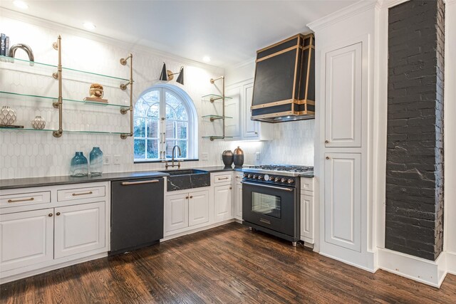 kitchen featuring range with gas stovetop, dishwasher, dark countertops, wall chimney range hood, and a sink