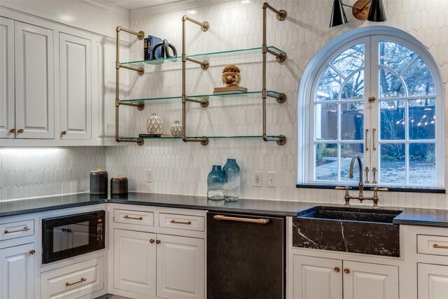 kitchen featuring black microwave, a sink, white cabinets, dark countertops, and plenty of natural light