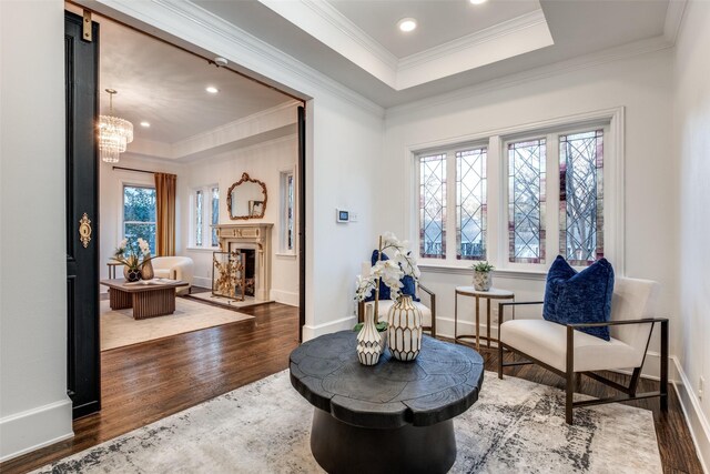 sitting room featuring a fireplace, a raised ceiling, ornamental molding, wood finished floors, and baseboards