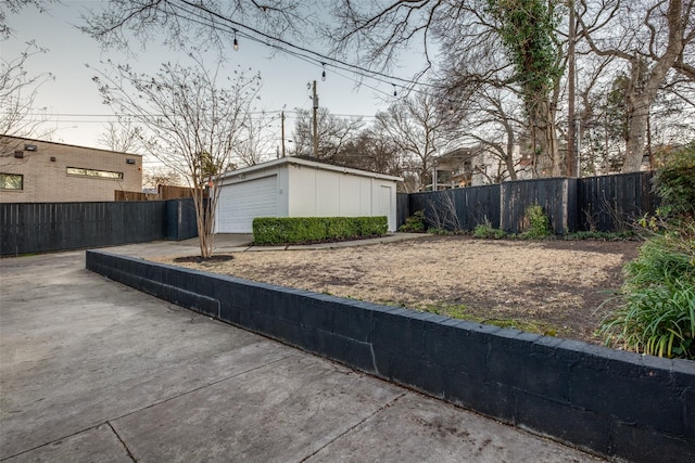 exterior space with driveway, an outdoor structure, fence, and a detached garage