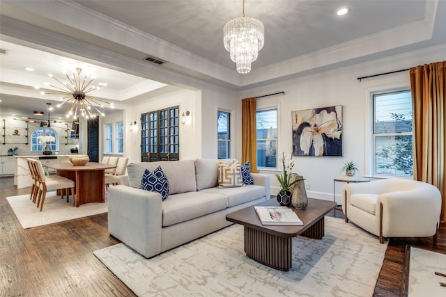 living room with a tray ceiling, visible vents, hardwood / wood-style floors, and an inviting chandelier