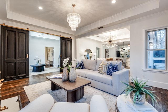 living area featuring a chandelier, a tray ceiling, and a barn door